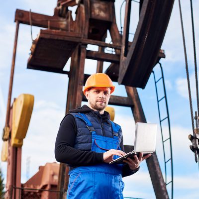 oil-engineer-with-a-laptop-standing-next-to-an-oil-DLZ7RBS